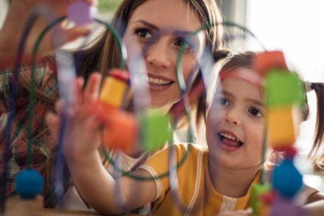 Niña de Educación infantil jugando con figuras de colores